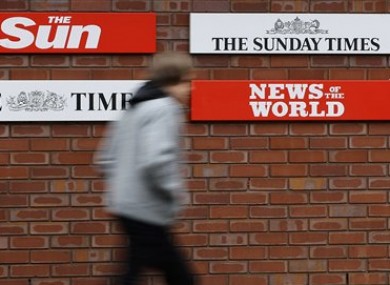 Jan. 27, 2011 file photo of a pedestrian he passes signs at the entrance to News International in Wapping, London.