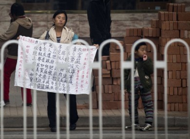 A Chinese petitioner holds a protest banner to seek justice for her dead son near a court house, where jailed activist Wang Lihong attends her court appeal case in Beijing, China, Thursday, Oct. 20, 2011.
