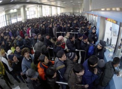 In this file photo released by China's Xinhua news agency, passengers queue in line to buy train tickets at Shenyang North Railway Station in Shenyang, capital of northeast China's Liaoning province.