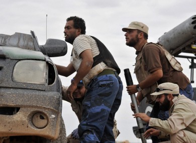 Libyan revolutionary fighters take cover outside the city of Sirte yesterday