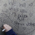 Apolline Arnaud, 12, a neighbour of Steve Jobs, writes a message in front of Jobs' house in Palo Alto, California. (AP Photo/Paul Sakuma)