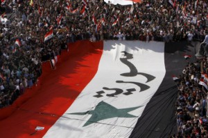 Pro-Syrian regime protesters, carry a giant Syrian flag during a demonstration against the Arab League decision to suspend Syria, in Damascus earlier today.