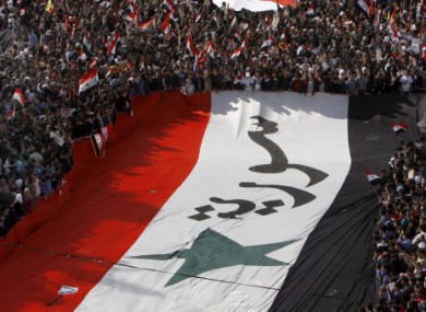 Pro-Syrian regime protesters, carry a giant Syrian flag during a demonstration against the Arab League decision to suspend Syria, in Damascus earlier today.