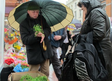 Flower seller Jimmi Lee, 55, sells a sprig of shamrock to shopper Catherine Fahy, 45, in Dublin today.