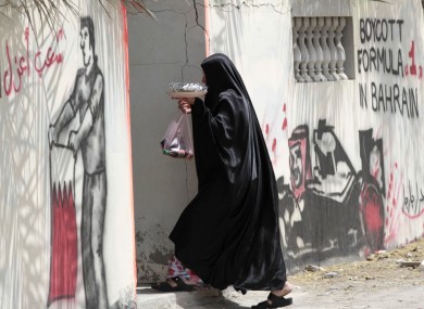 A woman in Barbar, Bahrain enters a house, where the outer walls are spayed with anti Grand Prix graffiti