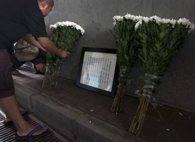 A man places flowers next to a frame with the names of flood's victim under a railway bridge, where a motorist drowned a week ago in Beijing, China Saturday, July 28, 2012