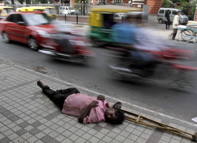 An Indian man sleeps on a pavement as traffic moves past in Ahmadebad.