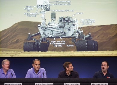 Scientists comment on the seven cameras aboard the Curiosity Mars Rover, background, during a media briefing of the Mars Science Laboratory