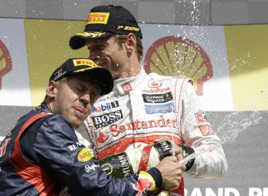 McLaren Mercedes driver Jenson Button of Britain, winner, top, celebrates sprays champagne with second place Red Bull driver Sebastian Vettel of Germany.