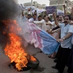Pakistani traders burn a representation of a US flag next to burning tires during a rally in Islamabad, Pakistan today. (AP Photo/Anjum Naveed)