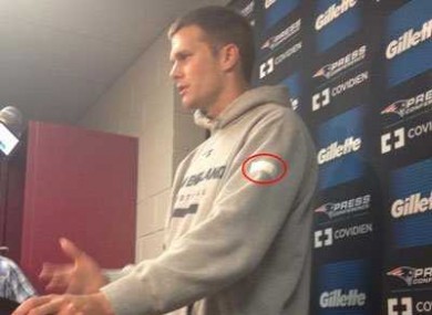 Tom Brady covers up the Nike 'swoosh' at a recent press conference.