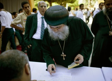 A Coptic clergyman registers for voting with election workers during the new Coptic Pope elections at the main Coptic cathedral in Cairo.