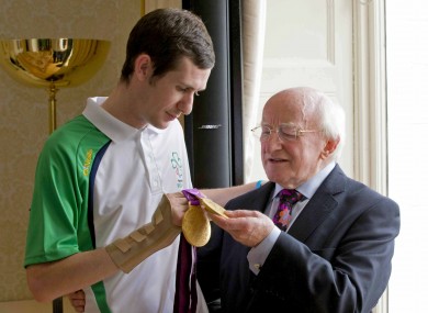 Double gold medal winner Michael McKillop shows off his prizes to President Michael D. Higgins at the Aras yesterday.