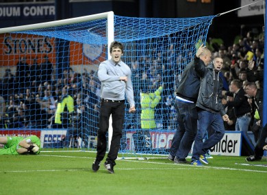 Sheffield Wednesday goalkeeper Chris Kirkland lays on the ground after being struck by a Leeds United fan as other fans run onto the pitch.