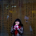 A Chinese woman holds a cup of hot drink as she take a rest along a Hutong alley, in the winter in Beijing. The meteorological observatory issued an alert on cold wave, as Beijing suffered from a sharp decline of temperatures. (AP Photo/Andy Wong)