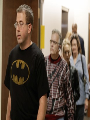 A man wears a Batman shirt as he arrives for court with other victims.