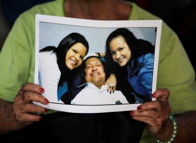 A woman holds a print of one of the photographs of Chavez released by the Venezuelan government on Friday